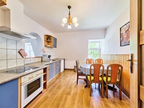 A modern kitchen with a Bosch stove, a wooden dining table with chairs, and a window with a view of greenery.