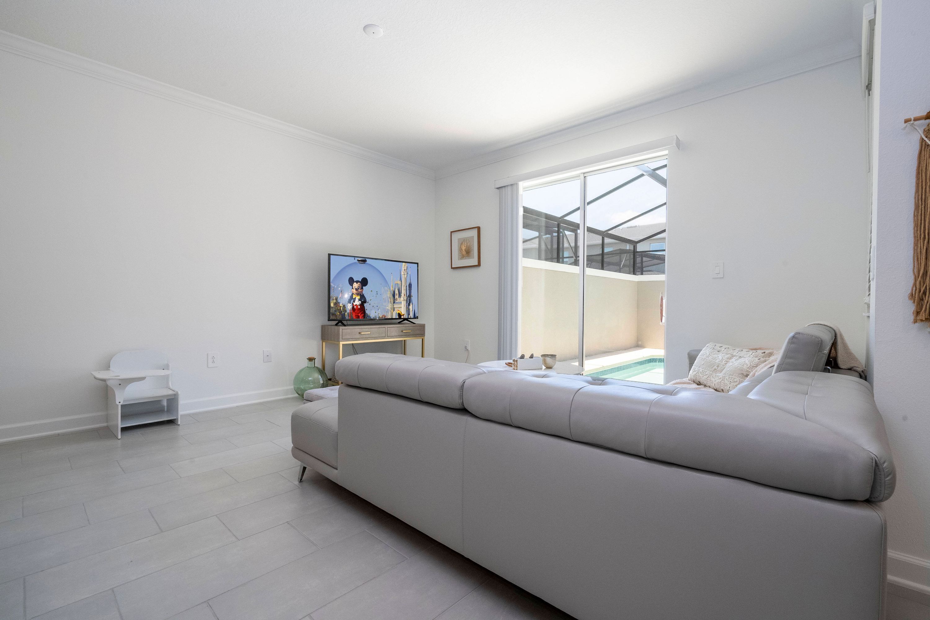 A modern living room with a large grey sofa, a television, and a small white table.