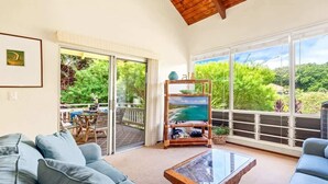 A spacious living area with a large window, a wooden coffee table, and a sofa. - Poipu Crater 24 – Stay in the Crater, A/C (Koloa)