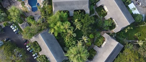 An aerial view of a resort with multiple buildings, a swimming pool, and lush greenery.