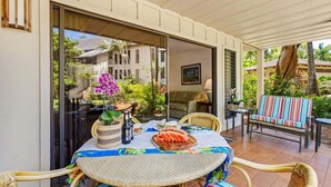A covered patio with a round table, wicker chairs, and a bench. - Waikomo Stream Villas 103 – Ground Floor, Garden View Retreat (Koloa)
