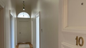Un pasillo con piso de madera, paredes blancas y una puerta numerada con el número 10.