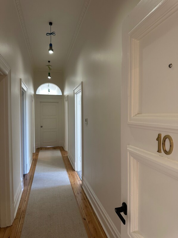 Un pasillo con piso de madera, paredes blancas y una puerta numerada con el número 10.