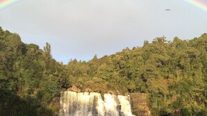 Une cascade sur laquelle se dessine un arc-en-ciel, le tout étant entouré d’une végétation luxuriante.