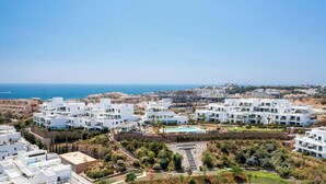 A coastal residential area with modern white buildings, a central swimming pool, and a clear view of the sea. - Golden Horizon | Terrace - pool - sea views (Mijas Costa)
