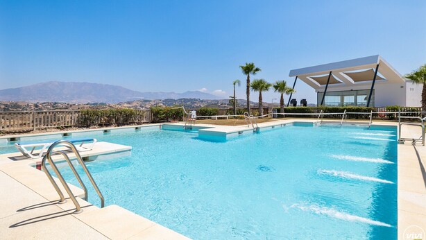 A swimming pool with clear blue water, surrounded by palm trees and a modern building with large windows. - Golden Horizon | Terrace - pool - sea views (Mijas Costa)