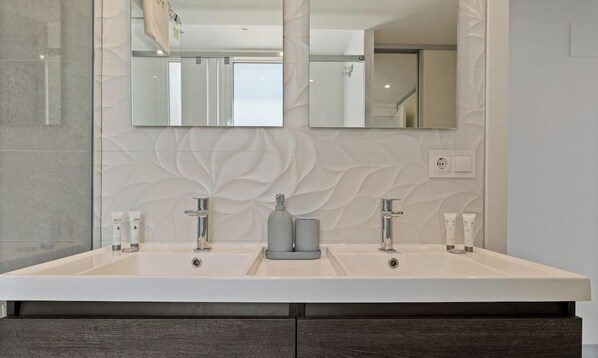 A bathroom with a double sink, a large mirror, and a decorative wall panel.