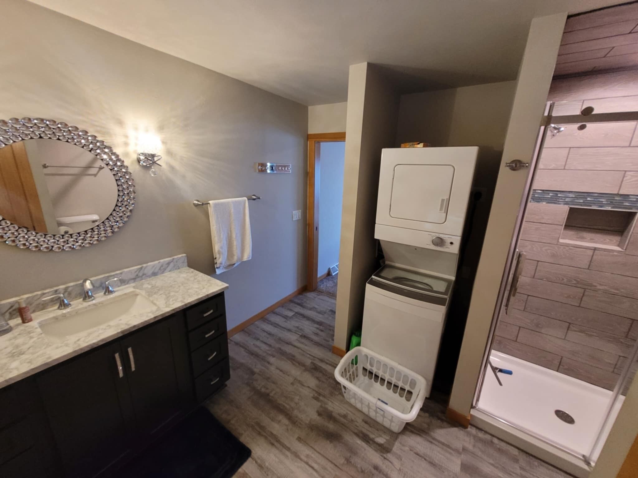 Un baño con tocador, espejo, toallero, lavadora y zona de ducha.