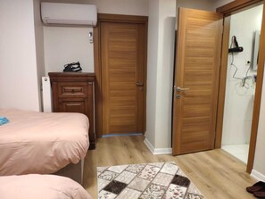 Ein Schlafzimmer mit einem Bett, einem Holzschrank, einem kleinen Tisch mit einem Telefon und einer Tür zu einem Badezimmer.