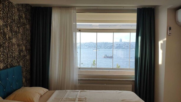 A hotel room with a large bed, a view of a body of water, and a cityscape in the background. - Cozy 2-bedroom apartment with Stunning Sea Views in enchanting Üsküdar, İstanbul (Üsküdar, İstanbul)