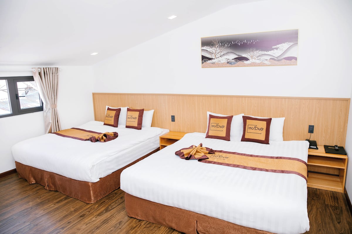Ett hotellrum med två sängar, trägavlar och en tavla på väggen.