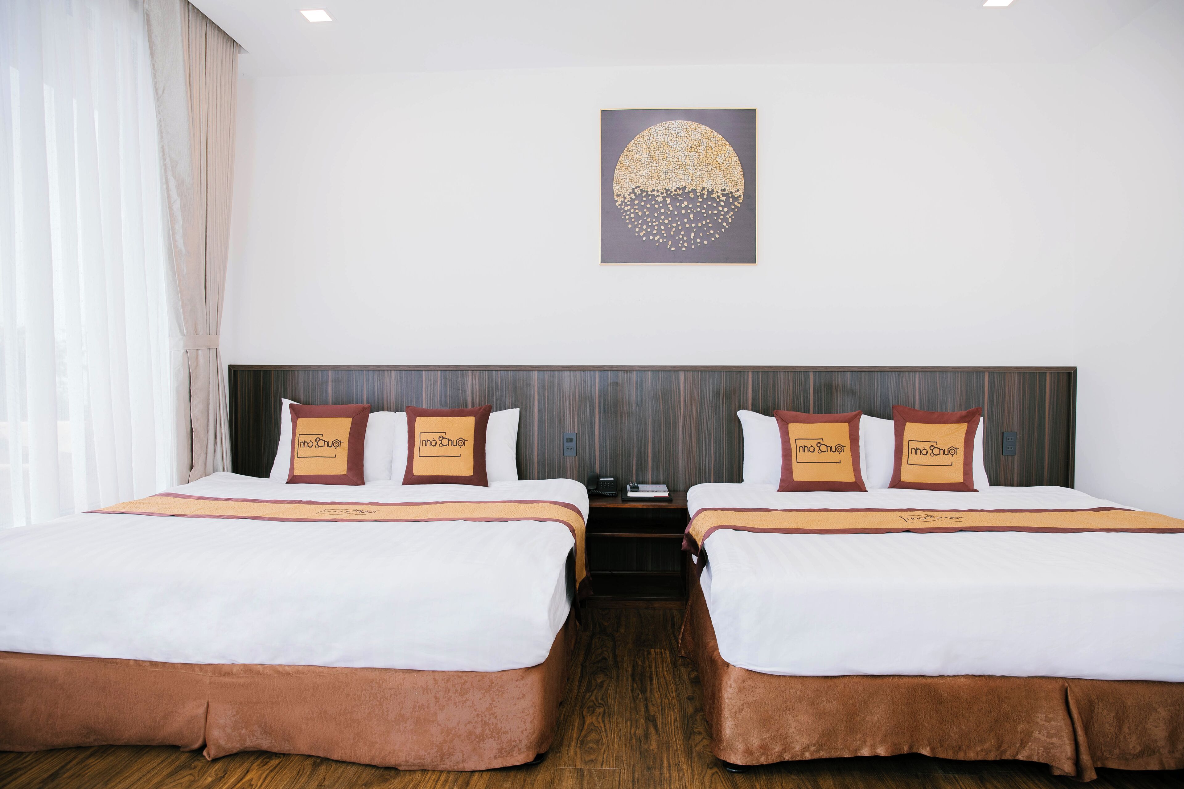 Habitación de hotel con dos camas, una mesita de noche y una obra de arte colgada en la pared.