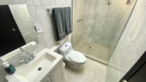 Et badeværelse med vask, toilet og bruser.