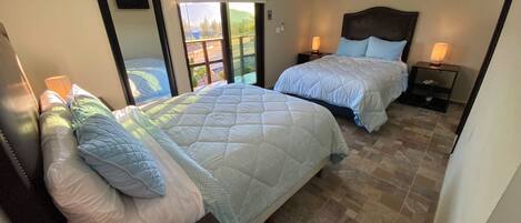 Un dormitorio con dos camas, un ventanal grande y un aire acondicionado.