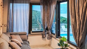 A modern bedroom with a large window, a sofa, and a potted plant. - Amazing home in Postira (Postira)