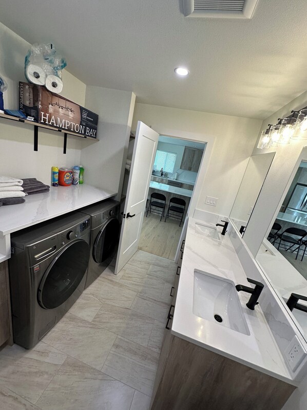 A modern bathroom with a large mirror, a sink, and a washing machine. - Cozy 3-bedroom house in peaceful Kenai with AC, WiFi (Kenai)