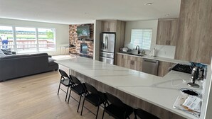 Una cocina moderna con una isla grande, electrodomésticos integrados y una pared decorativa de piedra.