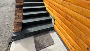 Una cabaña de madera con una escalera de piedra que lleva a una puerta.