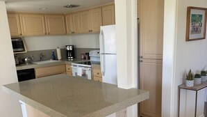 A modern kitchen with wooden cabinets, a granite countertop, and a built-in island.