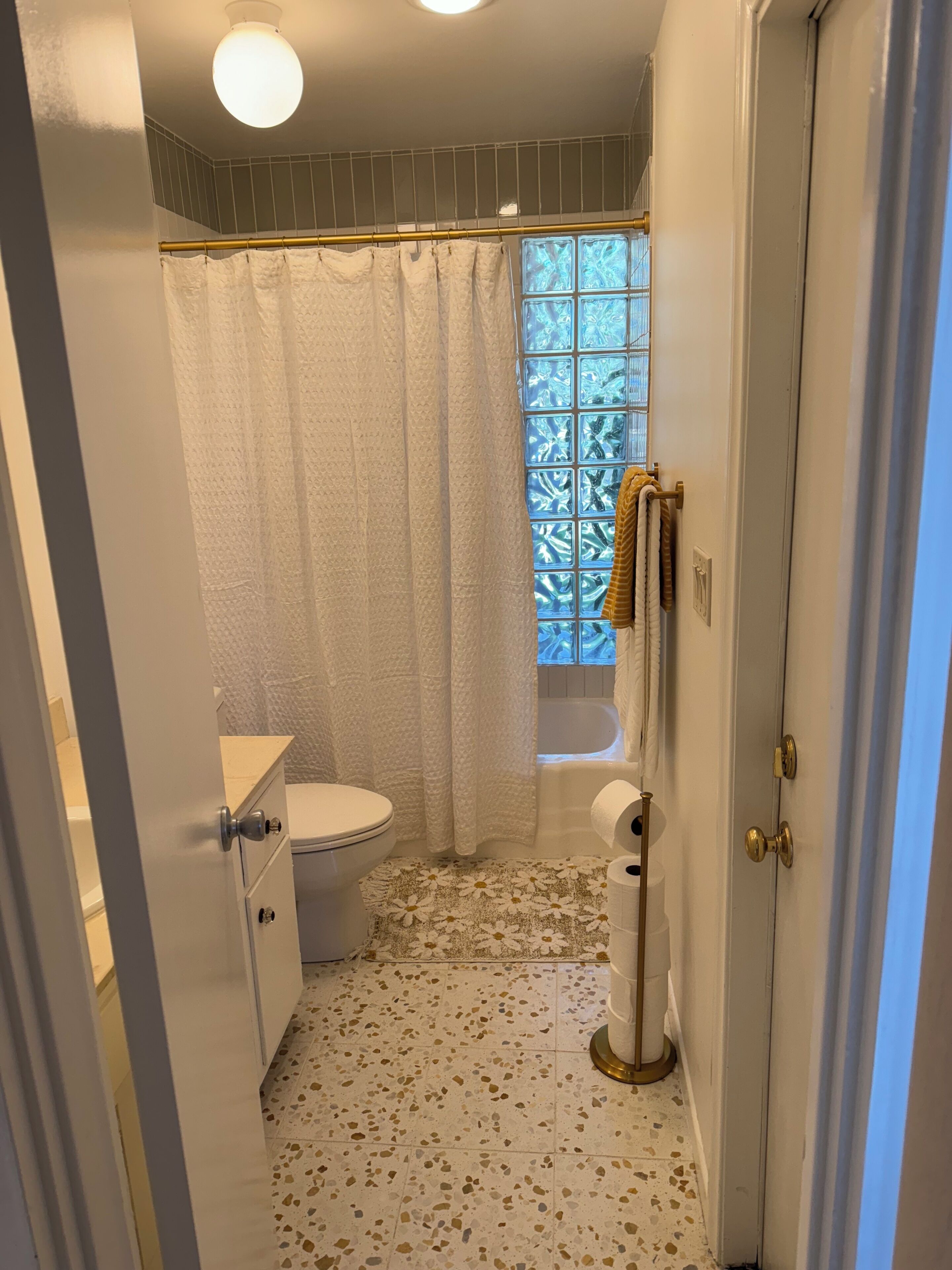 A bathroom with a toilet, a shower curtain, a bathtub, and a toilet paper holder.