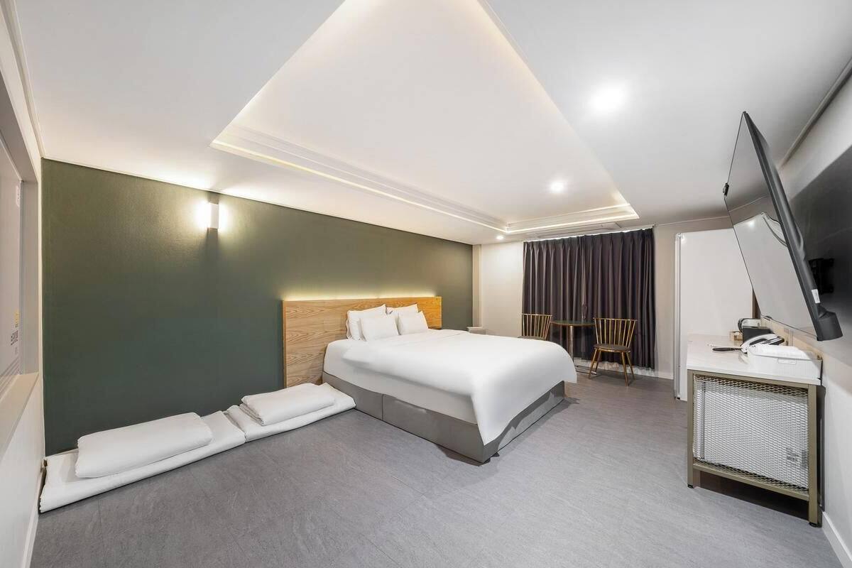 A modern hotel room with a large bed, a flat-screen TV, and a desk with a chair.
