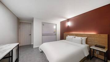 A hotel room with a large bed, a desk, and a wardrobe.