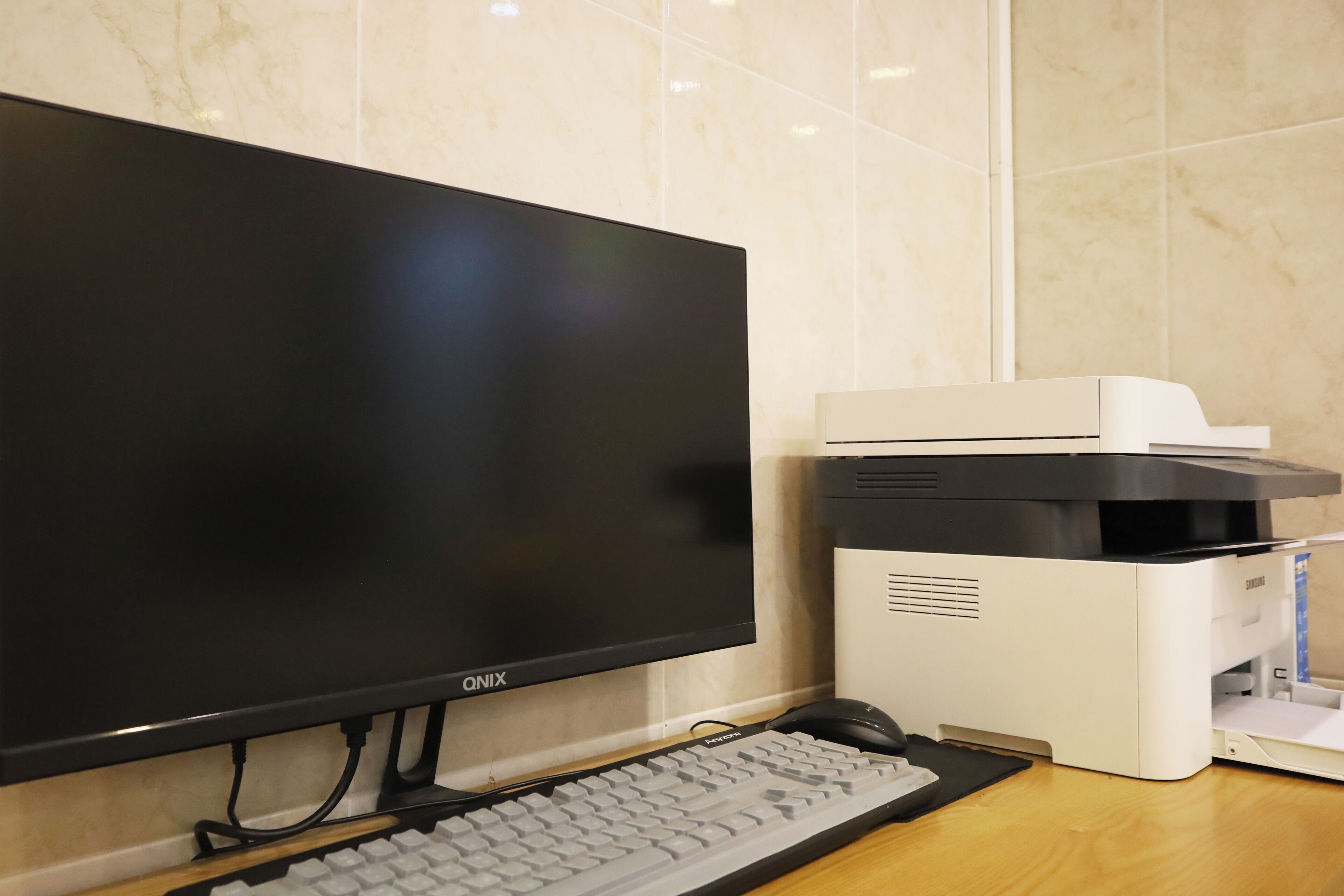 A computer setup with a monitor, keyboard, and printer on a wooden desk.