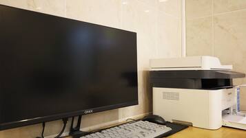 Un equipo de computadora con monitor, teclado e impresora sobre un escritorio de madera.