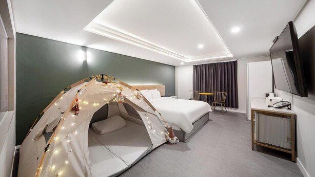 A hotel room with a bed, a small desk, a TV, and a tent-like structure with lights. - BRIGHTEN HOTEL (Jeonju)
