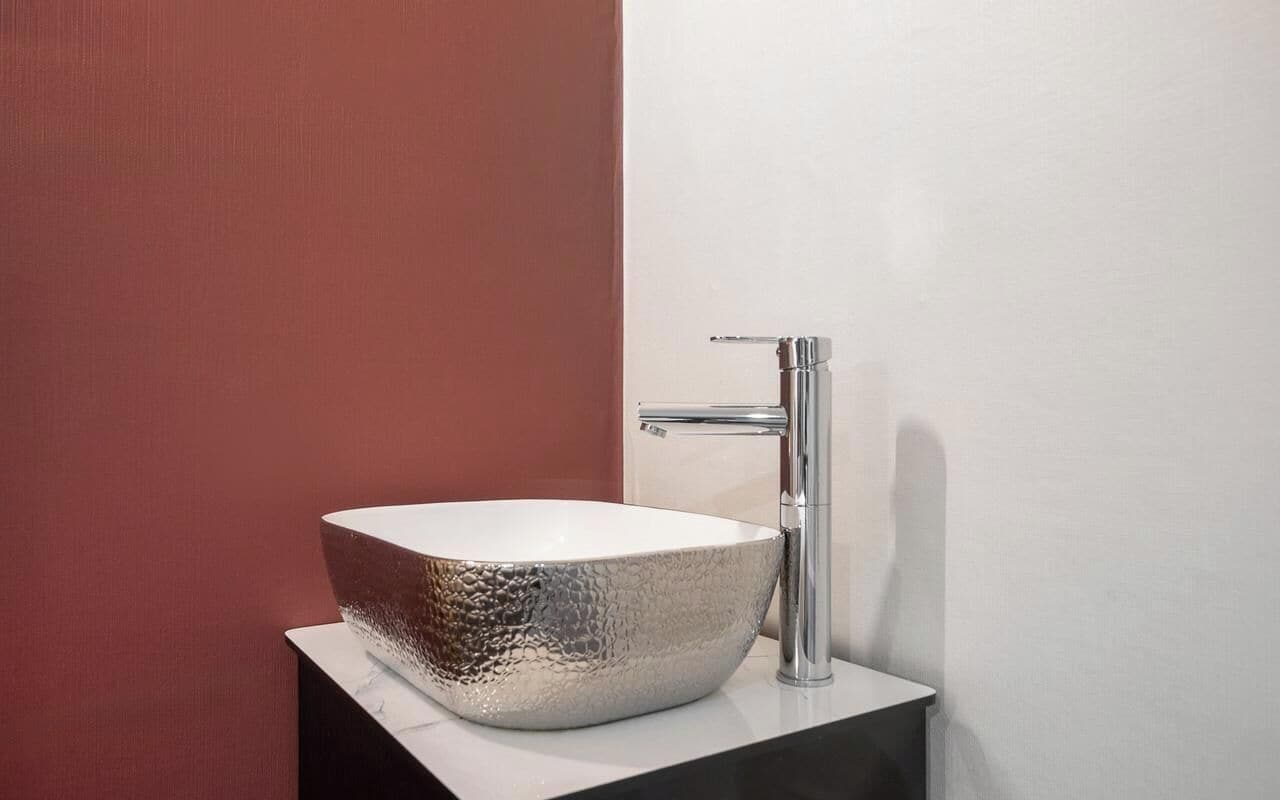 A modern bathroom with a large, textured vessel sink and a sleek chrome faucet.