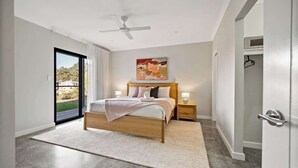Ein Schlafzimmer mit einem Bett, Nachttischen, einem Deckenventilator und einem großen Fenster.