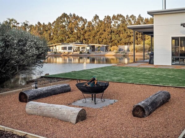 Un jardin avec un foyer, des bûches et un étang.