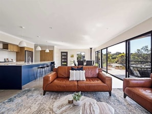 A modern living space with a leather sofa, a coffee table, and a kitchen area with bar stools.