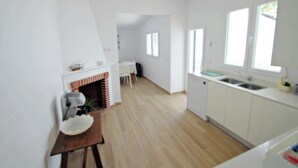 Eine moderne Küche mit weißen Schränken, Holzboden und einem Kamin aus Ziegelsteinen.