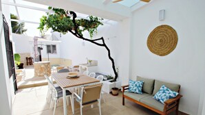 Eine sonnendurchflutete Terrasse mit Esstisch, Stühlen und einer Couch.