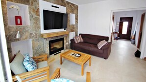 Ein Wohnzimmer mit Steinwand, Flachbildfernseher, Kamin, braunem Sofa und Couchtisch aus Holz.