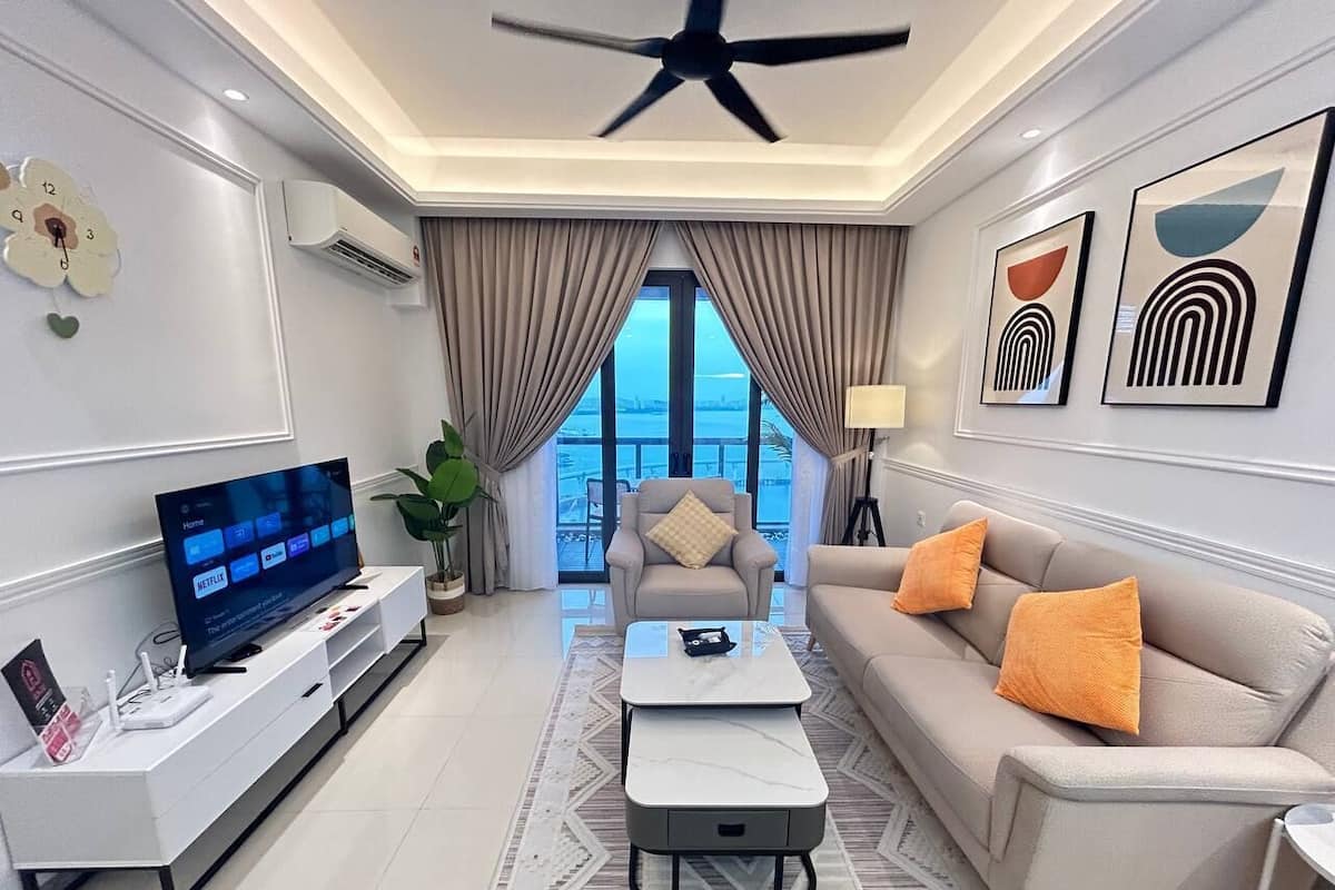 A modern living room with a flat-screen TV, a sofa, a coffee table, and a chair.