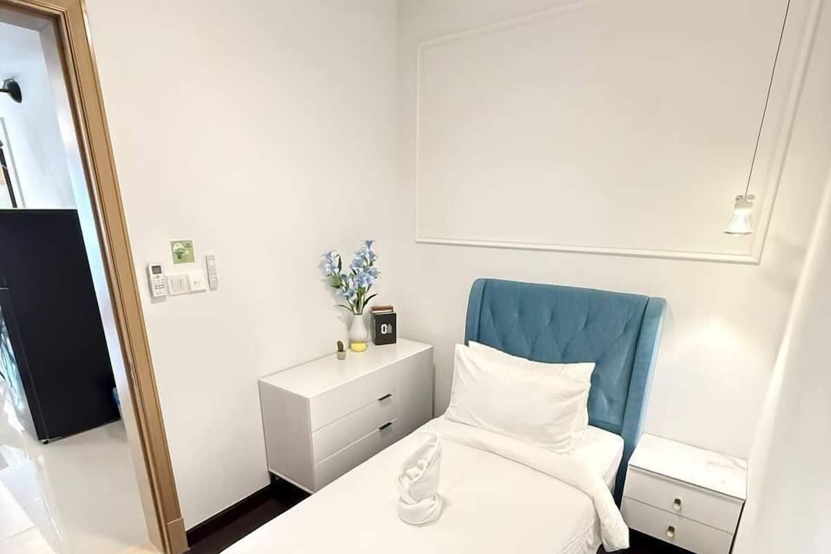 A modern hotel room with a large bed, a nightstand, a bedside table, and a ceiling fan.