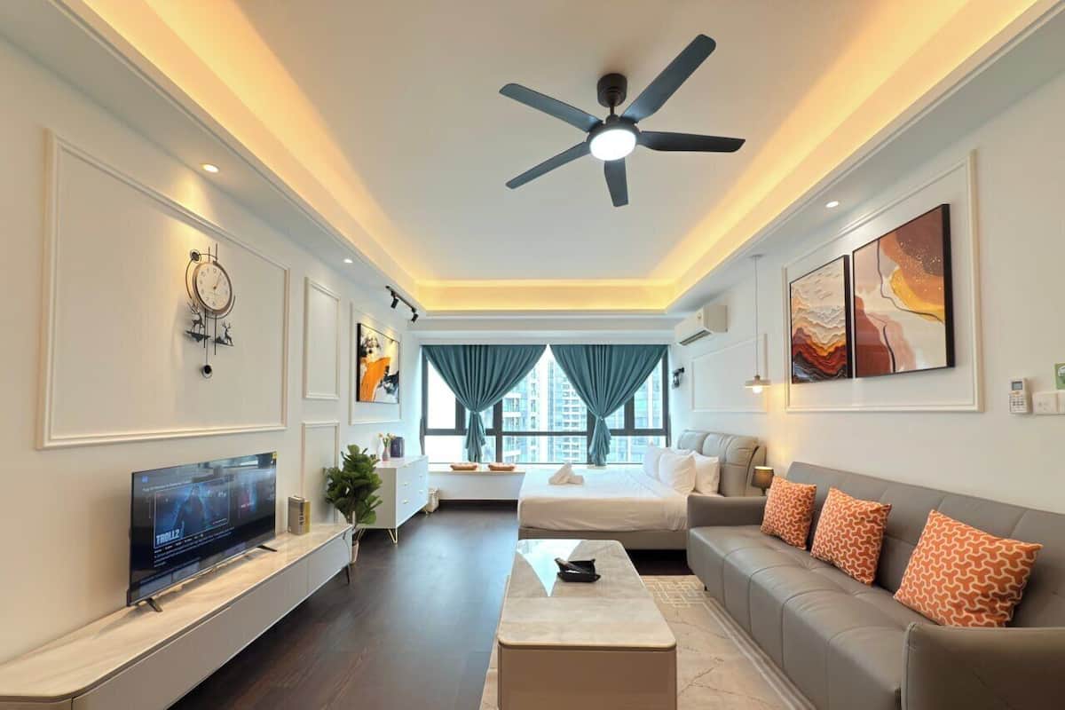 A modern living room with a flat-screen TV, a ceiling fan, a sofa set, and a large window with curtains.