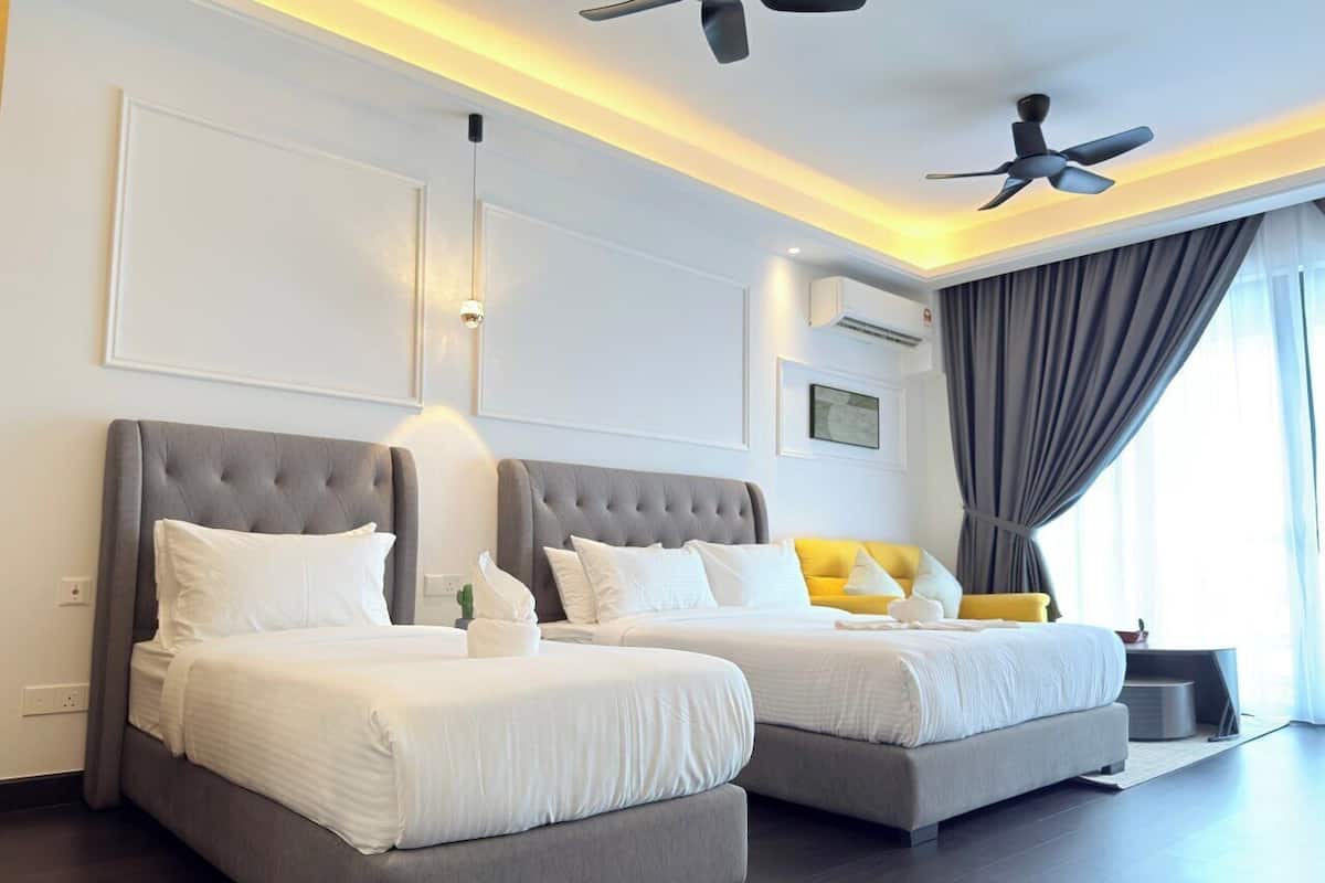 A hotel room with two beds, a ceiling fan, and a large window with curtains.