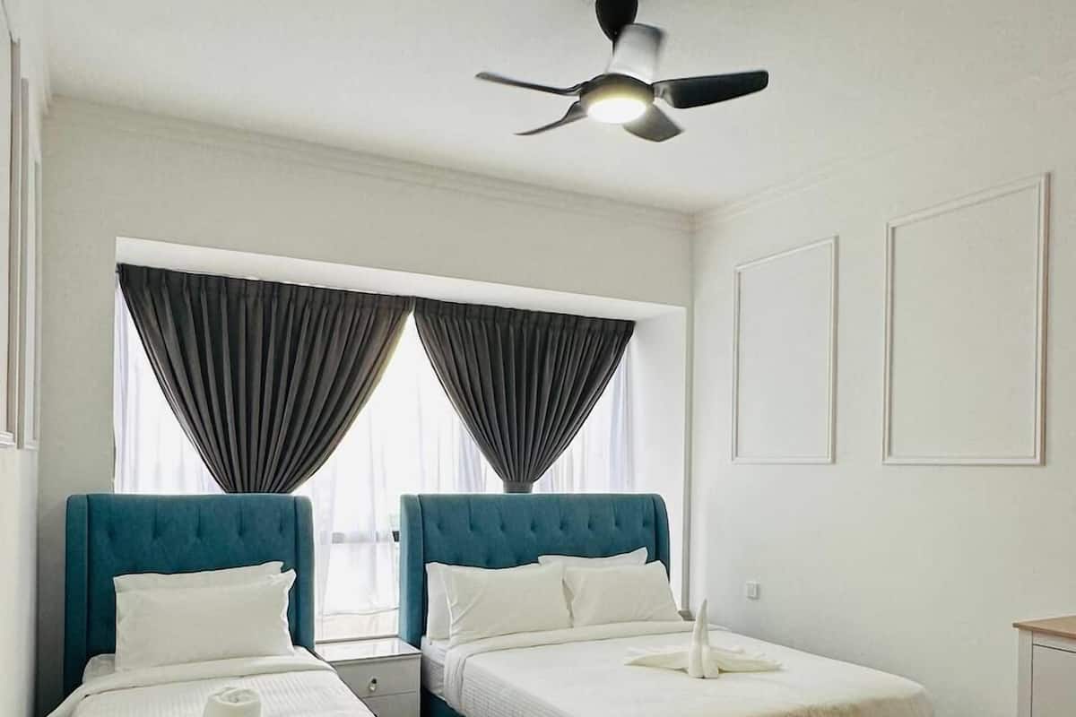 A hotel room with two single beds, a ceiling fan, and a window with curtains.