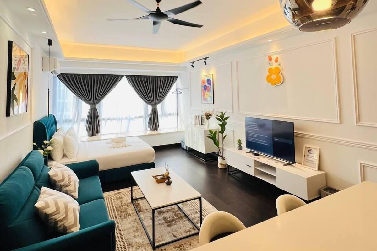 A modern living room with a sofa, coffee table, TV, and ceiling fan.