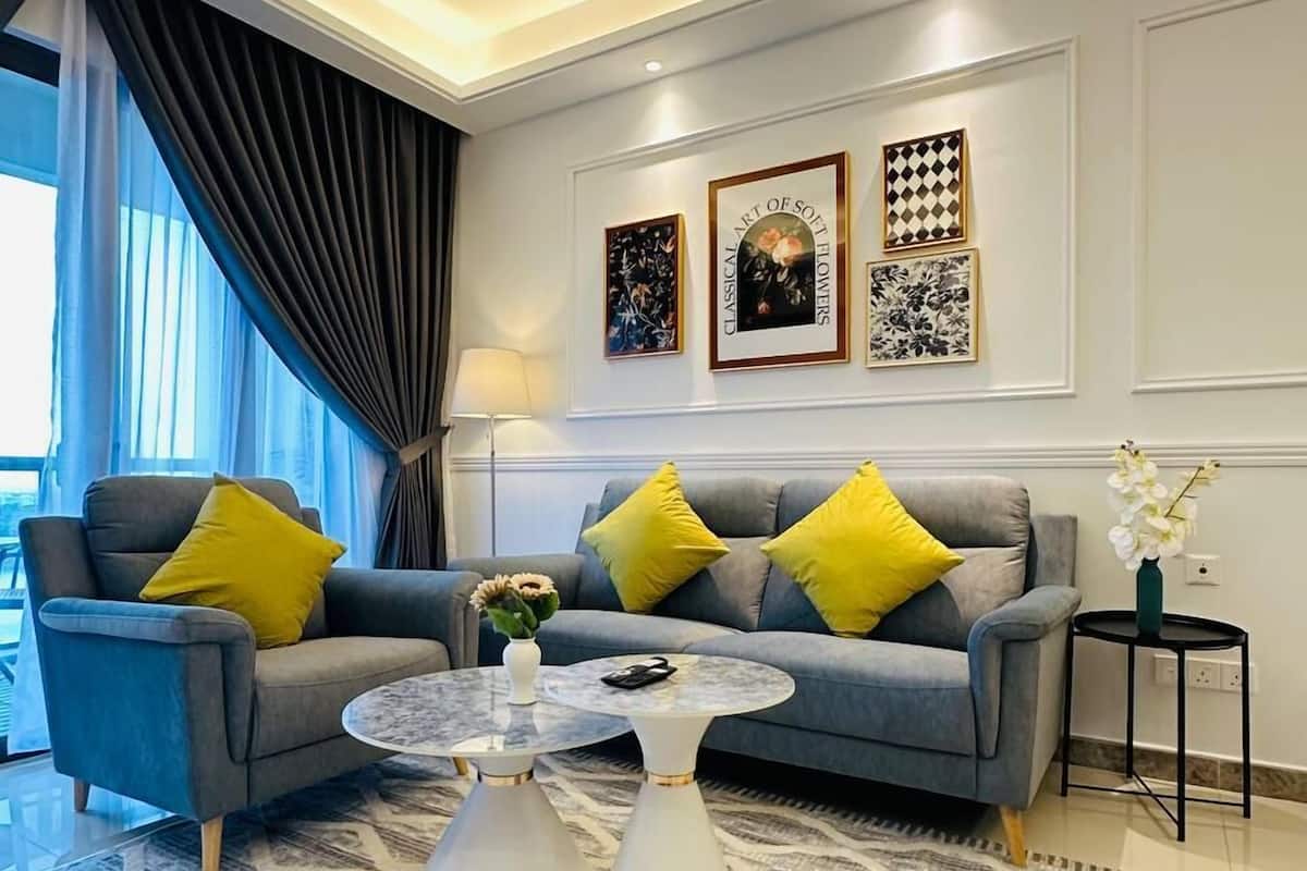 A modern living room with a grey sofa, yellow cushions, a round coffee table, and a patterned rug.