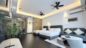 Una habitación de hotel moderna con dos camas, un sofá, una mesa de comedor y un ventilador de techo.