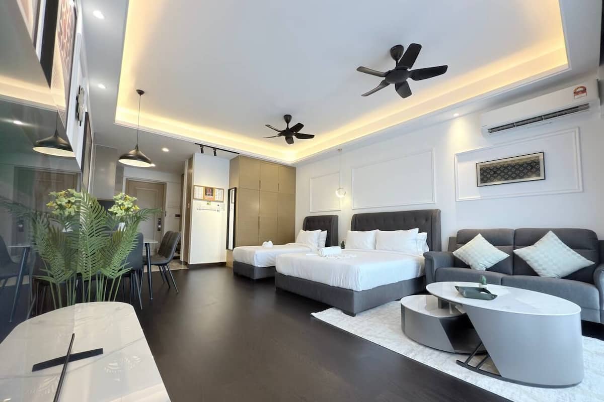 A modern hotel room with two beds, a sofa, a dining table, and a ceiling fan.