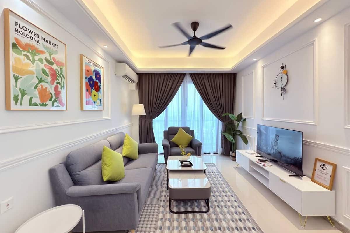 A modern living room with a grey sofa, a coffee table, a TV on a white stand, and a ceiling fan.