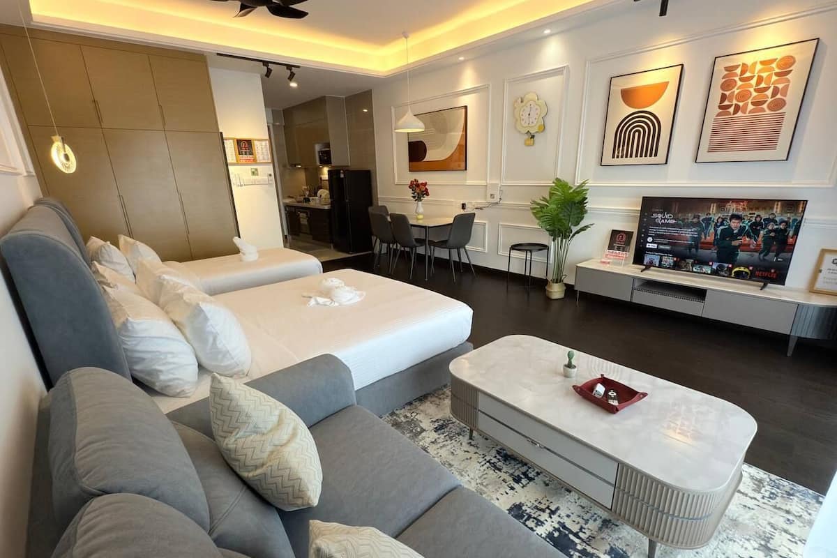 A modern living room with a grey sofa set, a white coffee table, and a TV displaying 'Squid Game'.