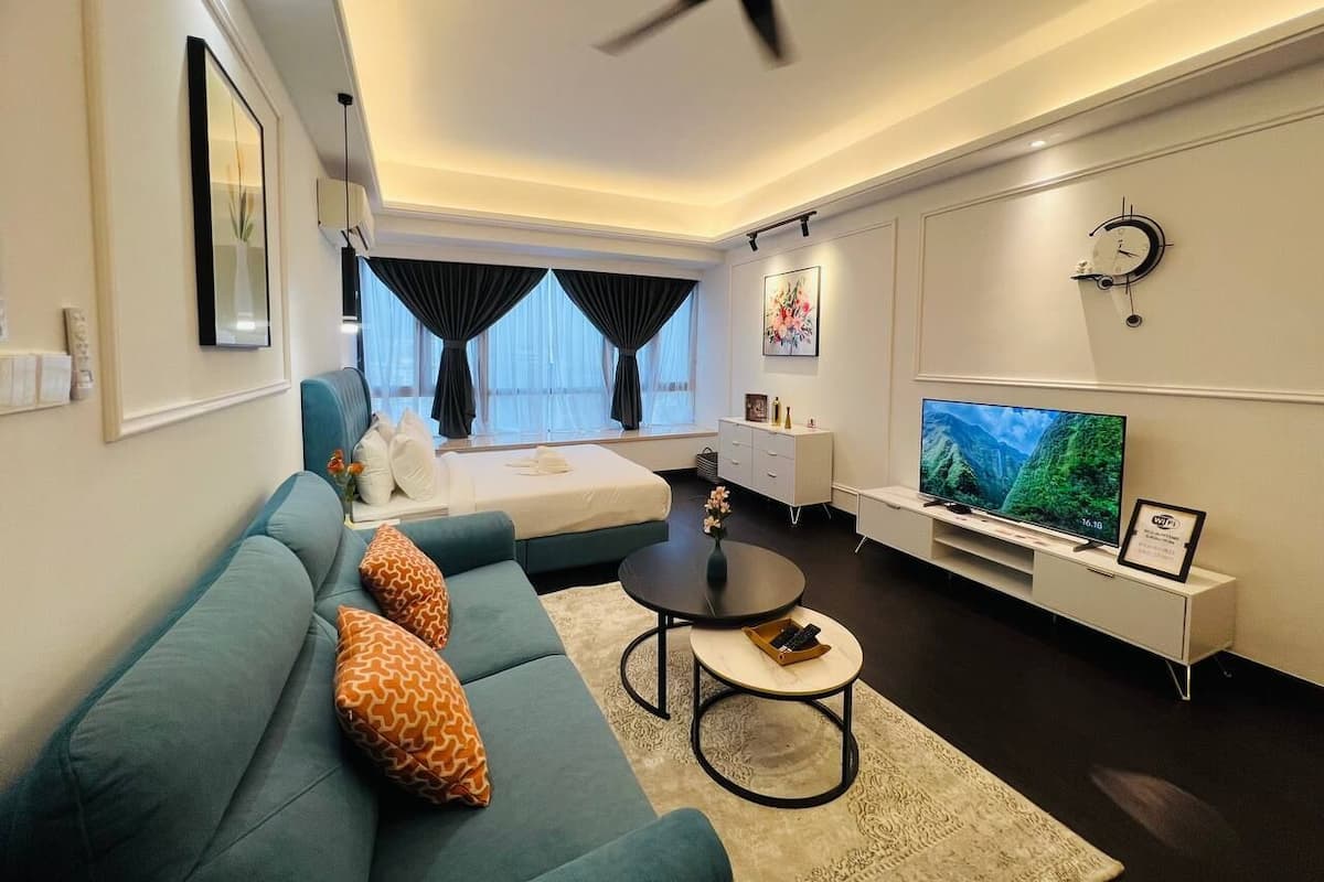 A modern living room with a sofa, coffee table, TV, and a bed.