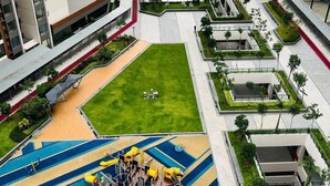 Un edificio residencial moderno con piscina en la azotea, zona de juegos infantiles y vistas a un río.