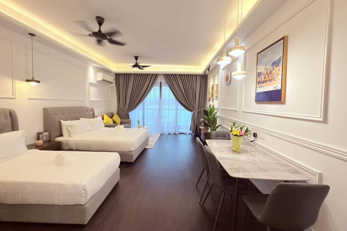 A hotel room with two beds, a dining table, and a ceiling fan.